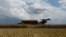 An agricultural worker operates a combine during a rapeseed harvesting in a field near the village Kyshchentsi in Cherkasy region, Ukraine, July 18, 2023. 