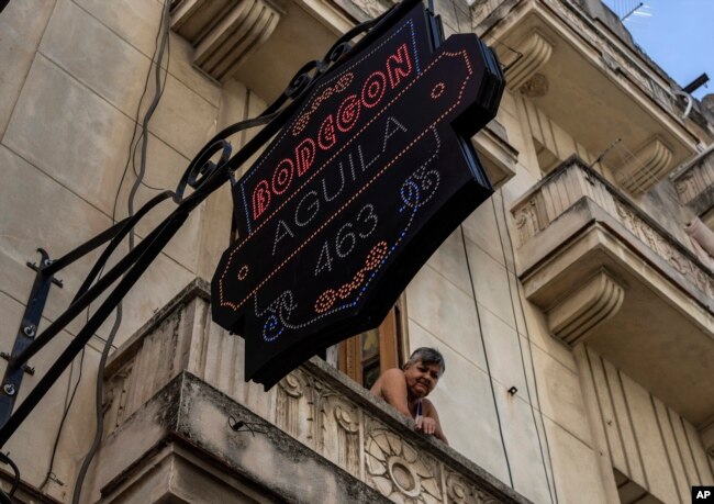 A resident looks out from her balcony over a private grocery store in Havana on Nov. 11, 2023.