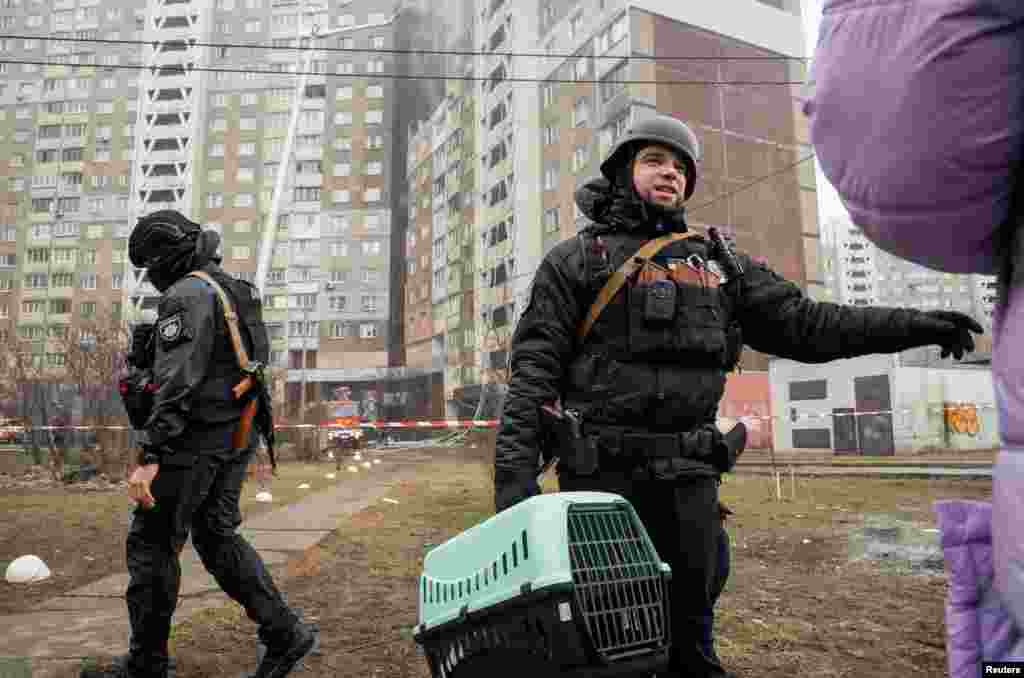 Офіцер поліції несе клітку з домашньою твариною, допомагаючи місцевому мешканцю покинути житловий будинок,&nbsp;пошкоджений під час російського ракетного удару на Київ.&nbsp;Фото&nbsp;REUTERS/Данило Антонюк,&nbsp;7 лютого, 2024 року &nbsp;