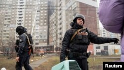在基辅，一名警察帮助民众离开被俄军导弹破坏的居民楼。(2024年2月7日)
