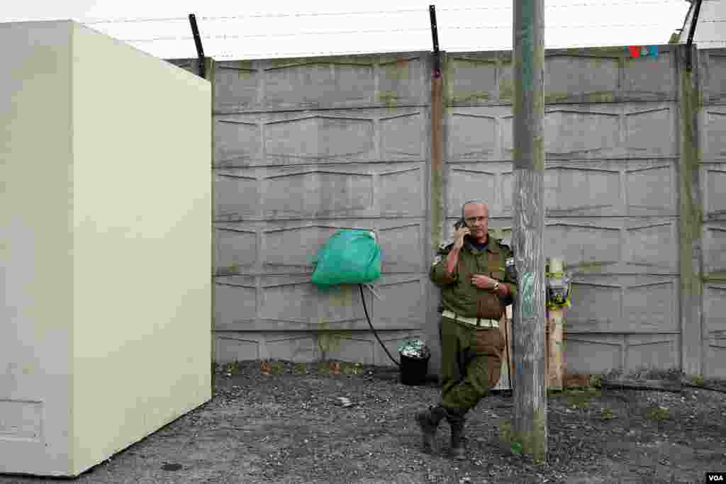 Un militar israelí habla por teléfono en l base Shura del ejército de Israel, donde se mantienen en contenedores refrigerados los restos de personas sin identificar, que fueron asesinadas por efectivos de Hamás en el ataqque a Israel del pasado 7 de octubre.