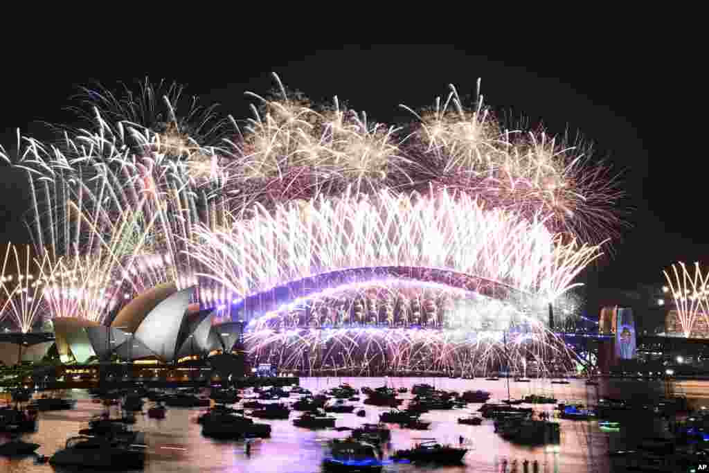 Fogos de artifício explodem sobre a Ópera de Sydney e sobre a Harbour Bridge durante as celebrações da passagem de ano em Sydney, a 1 de janeiro de 2024.