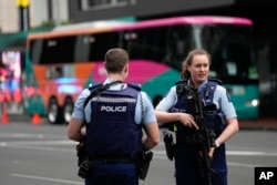 Armed New Zealand police officers stand outside a hotel housing a team from the FIFA Women's World Cup in the central business district following a shooting in Auckland, July 20, 2023.