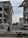 A local woman rides a bicycle on April 18, 2024, in front of a building destroyed by a Russian airstrike in the frontline town of Orikhiv, Ukraine. 