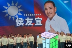 Hou Yu-ih (C), Taiwan presidential candidate 2024 from the main opposition party Kuomintang (KMT), poses for photographs in front of a screen showing himself during the 31th KMT Party Congress in New Taipei City, July 23, 2023.