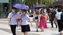 Para pejalan kaki menggunakan payung untuk melindungi dari panas sinar matahari di mal Siam Paragon, Bangkok, 1 April 2024. (Foto: Lilian Suwanrumpha/AFP)