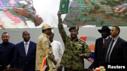 FILE — Sudan's Head of Transitional Military Council, Gen. Abdel Fattah Al-Burhan, celebrates the signing of the power sharing deal, alongside his deputy and now leader of the paramilitary Rapid Support Forces, Mohamed Dagalo,in Khartoum, Aug. 17, 2019.