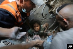 Palestinians try to pull a girl out of the rubble of a building that was destroyed by Israeli airstrikes in Jabaliya refugee camp, northern Gaza Strip, Nov. 1, 2023.