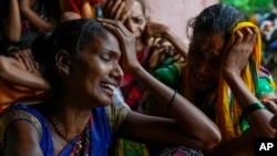 Family members of people trapped under rubble wail after a landslide washed away houses in Raigad, India, July 20, 2023. 