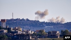 FILE - A picture taken from from the southern Lebanese village of Tayr Harfa, near the border with Israel shows smoke billowing near an Israeli outpost from rockets fired by Hezbollah on Dec. 15, 2023. 