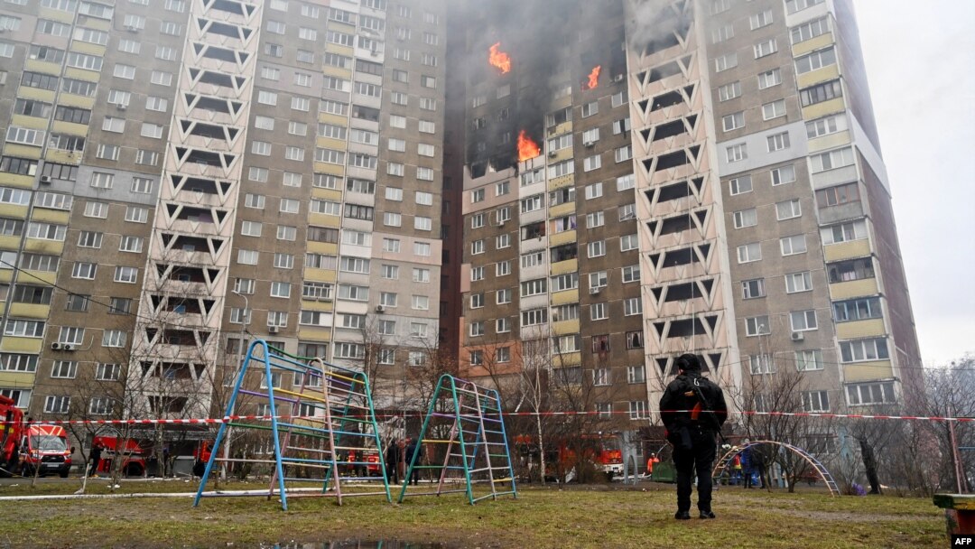 Seorang petugas penegak hukum berdiri di samping sebuah bangunan tempat tinggal, rusak akibat serangan rudal di Kyiv, Ukraina, pada 7 Februari 2024. (Foto: AFP)