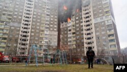 Seorang petugas penegak hukum berdiri di samping sebuah bangunan tempat tinggal, rusak akibat serangan rudal di Kyiv, Ukraina, pada 7 Februari 2024. (Foto: AFP)