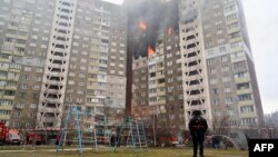 A law enforcement officer stands next to a residential building, damaged as a result of a missile attack in Kyiv, Ukraine, on Feb. 7, 2024.