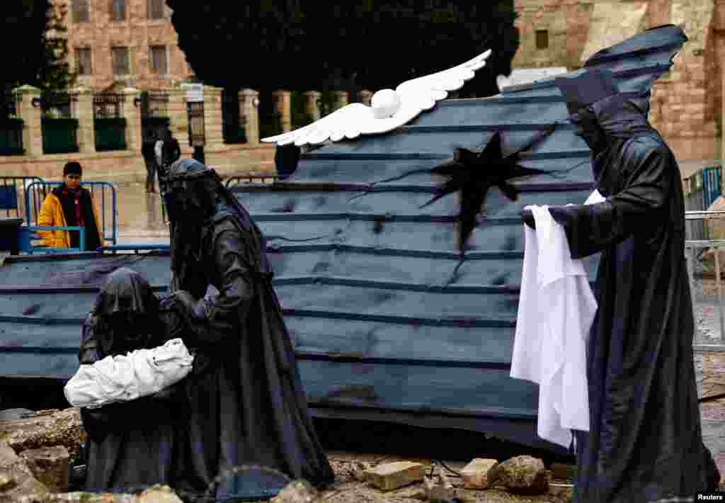 A Christmas installation of a grotto with figures standing amid rubble surrounded by a razor wire, is displayed outside the Church of the Nativity on Manger Square in Bethlehem, in the Israeli-occupied West Bank.