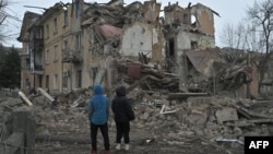 Residentes locales se encuentran entre los escombros de un edificio residencial parcialmente destruido por un ataque con misiles en la ciudad de Selydove, región de Donetsk, Ucrania, el 8 de febrero de 2024.