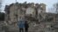 Local residents stand among debris of a residential building partially destroyed by a missile attack in the town of Selydove, Donetsk region, Ukraine, on Feb. 8, 2024.