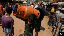 বাংলাদেশের কক্সবাজার জেলার একটি শরণার্থী শিবিরে একজন রোহিঙ্গা শরণার্থী একটি গ্যাস সিলিন্ডার বহন করে নিয়ে যাচ্ছে। ৯ মার্চ, ২০২৩। (ফাইল ছবি) 