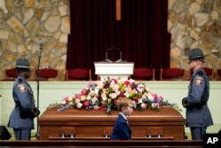 A young mourner walks past the casket before the funeral service for former first lady Rosalynn Carter at Maranatha Baptist Church, in Plains, Georgia, Nov. 29, 2023.