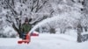 FILE - A person removes snow from a sidewalk during a winter storm in Doylestown, Pa., Feb. 13, 2024. 