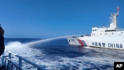 In this photo provided by the Philippine Coast Guard, a Chinese Coast Guard ship, right, uses its water cannons on a Philippine vessel as it approaches Scarborough Shoal in the disputed South China Sea on Dec. 9, 2023.