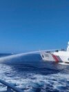 In this photo provided by the Philippine Coast Guard, a Chinese Coast Guard ship, right, uses its water cannons on a Philippine vessel as it approaches Scarborough Shoal in the disputed South China Sea on Dec. 9, 2023.