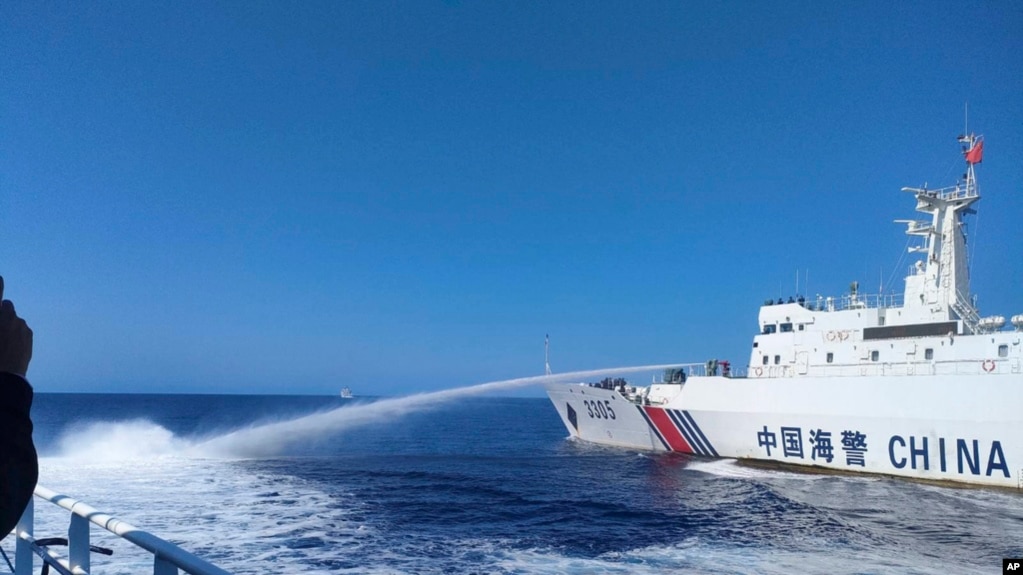 资料照片：在菲律宾海岸警卫队提供的这张照片中，一艘中国海警船(右)在2023年12月9日接近有争议的南中国海斯卡伯勒浅滩（中国称黄岩岛）时，向一艘菲律宾船只发射水炮。(Philippine Coast Guard via AP)(photo:VOA)