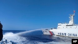 在菲律賓海岸警衛隊提供的這張照片中，一艘中國海警船(右)在2023年12月9日接近有爭議的南中國海斯卡伯勒淺灘（中國稱黃岩島）時，向一艘菲律賓船隻發射水炮。(Philippine Coast Guard via AP)