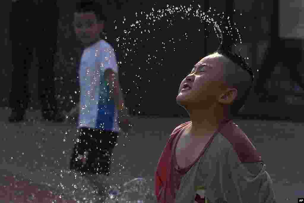 A child cools off playing at a fountain in Beijing. Local media reported that June temperatures in the Chinese capital broke its record with 39.4 celsius on Friday.