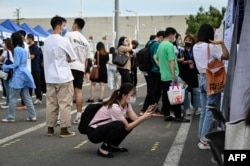 China's slowing economy has left millions of young people fiercely competing for an ever-slimming raft of jobs and facing an increasingly uncertain future. In this photo taken Aug. 26, 2022, a woman is using her phone during a job fair in Beijing.
