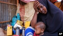 FILE - Hadiiq Abdulle Mohamed holds one of her children as she speaks during an interview with Associated Press at an internally displaced people camp on the outskirts of Mogadishu, Somalia, March 24, 2023. 