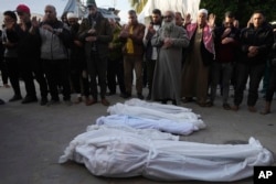 Palestinians pray over the bodies of a woman and her four children killed in the Israeli bombardments of the Gaza Strip at Al Aqsa Hospital in Deir al Balah on Feb. 20, 2024.
