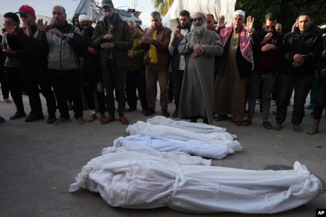 Palestinians pray over the bodies of a woman and her four children killed in the Israeli bombardments of the Gaza Strip at Al Aqsa Hospital in Deir al Balah on Feb. 20, 2024.
