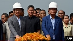 FILE - Cambodia's Prime Minister Hun Sen, right, and China's ambassador to Cambodia, Wang Wentian, press buttons during a groundbreaking ceremony for the construction of an expressway from Phnom Penh to Bavet city, in Phnom Penh, June 7, 2023.