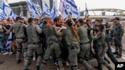 Israeli police scuffle with demonstrators blocking a road during a protest against plans by Prime Minister Benjamin Netanyahu's government to overhaul the judicial system in Tel Aviv, Israel, March 23, 2023.