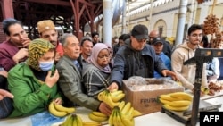 FILE—A produce merchant weighs bananas for customers at the Central Market in Tunis on March 23, 2023, as people shop on the first day of the Muslim holy fasting month of Ramadan.