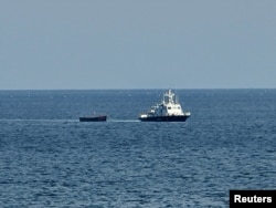 Sebuah kapal militer Korea Selatan menarik kapal Korea Utara yang membawa orang-orang yang diyakini berusaha membelot dari negara tersebut, ke pelabuhan di Yangyang, Korea Selatan, 24 Oktober 2023. (Foto: Yonhap via REUTERS)