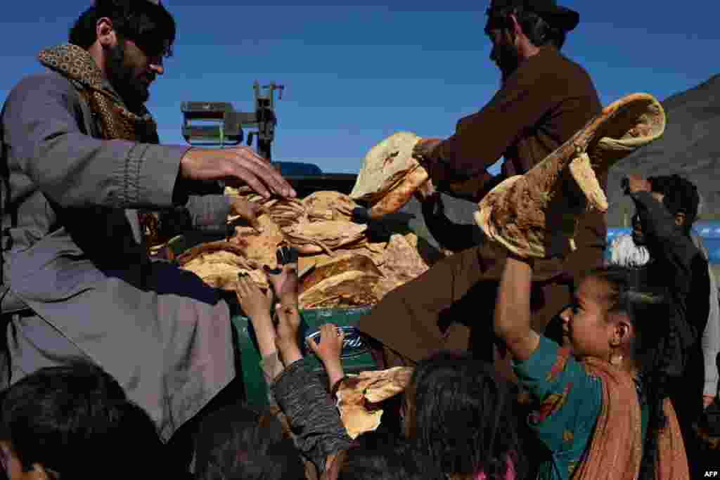 Afghan refugees' children receive bread from a local charity at a makeshift camp upon their arrival from Pakistan, near the Afghanistan-Pakistan Torkham border in Nangarhar province, Nov. 12, 2023.