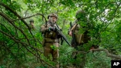 (FILE) Russian soldiers walk through a forest in an undisclosed location in Ukraine in this photo, taken from video released by the Russian Defense Ministry Press Service on Wednesday, June 12, 2024.