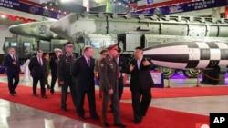 In this photo provided by the North Korean government, North Korean leader Kim Jong Un, right, leads a Russian delegation headed by Defense Minister Sergei Shoigu through an arms exhibition in Pyongyang, July 26, 2023.