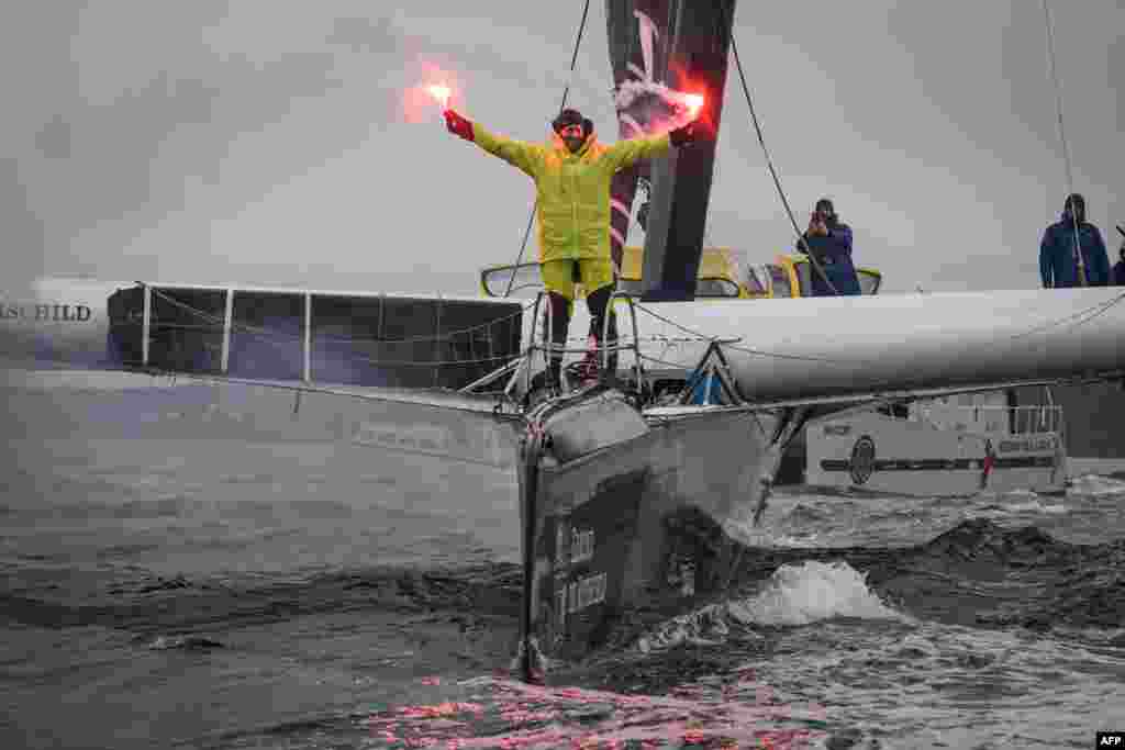 French skipper Charles Caudrelier holds burning flares&nbsp;onboard his Ultim multihull Gitana-Edmond de Rothschild as he sails into a port after winning the Arkea Ultim challenge around-the-world solo sailing race, in Brest, western France.