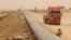 FILE - Workers set up a natural gas pipeline during a dust storm at Iraq's border with Iran, in Basra, southeast of Baghdad, April 12, 2016. 