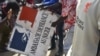 Des manifestants tiennent une pancarte arrachée à l'ambassade de France à Niamey lors d'une manifestation qui a suivi un rassemblement de soutien à la junte nigérienne à Niamey le 30 juillet 2023.