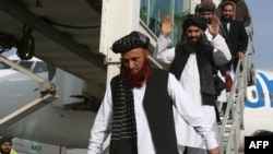 Abdul Karim (kiri) dan Abdul Zahir (tengah), dua mantan tahanan yang ditahan di pusat penahanan AS di Teluk Guantanamo, tiba di bandara Kabul di Kabul, Afghanistan, 12 Februari 2024.