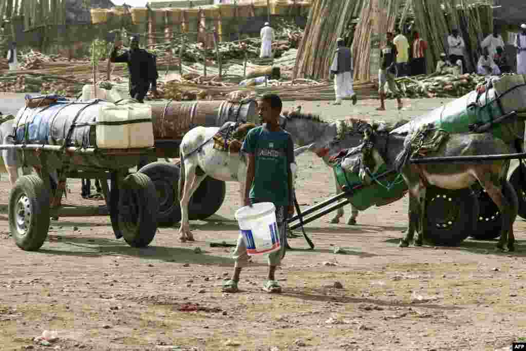 Луѓето користат буриња поставени на колички влечени од магариња за транспорт на вода во јужниот судански град Гадариф, Судан, 21 април, 2024 година.