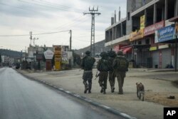 FILE — Israeli soldiers patrol the Palestinian town of Hawara, which emptied after the Israeli military closed shops and banned Palestinian vehicles from the main road in the wake of Palestinian militant attacks and settler violence, Nov. 12, 2023.