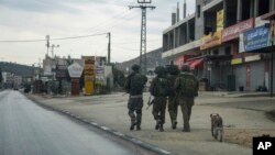 Tentara Israel berpatroli di Kota Hawara, Palestina, yang kosong setelah militer Israel memerintahkan untuk menutup toko-toko dan melarang kendaraan melintas di jalan utama di tengah meningkatnya serangan oleh para pemukim Israel, 12 November 2023. (Foto: Mahmoud Illean/AP)
