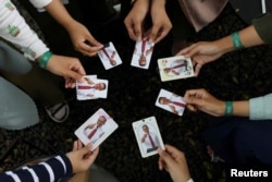 Orang-orang menunjukkan foto Capres Anies Baswedan saat Acara Humanies Cup Sleeve di kafe Kopi Nako di Jakarta, 4 Februari 2024. (REUTERS/Ajeng Dinar Ulfiana)