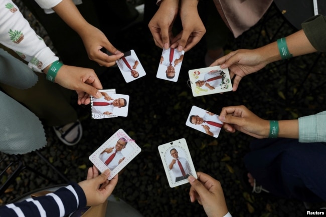 Orang-orang menunjukkan foto Capres Anies Baswedan saat Acara Humanies Cup Sleeve di kafe Kopi Nako di Jakarta, 4 Februari 2024. (REUTERS/Ajeng Dinar Ulfiana)