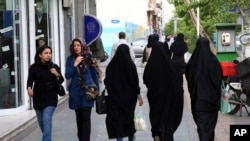 FILE - Iranian women make their way along a sidewalk in downtown Tehran, Apr. 26, 2016.