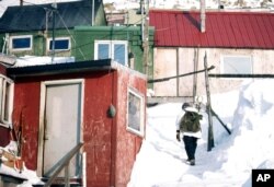 FILE - A resident of Little Diomede Island, Alaska, walks up the snow-covered trail that leads to his small plywood house in this undated file photo.